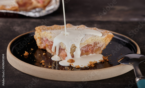 Rhubarb pie with double cream being poured over it.