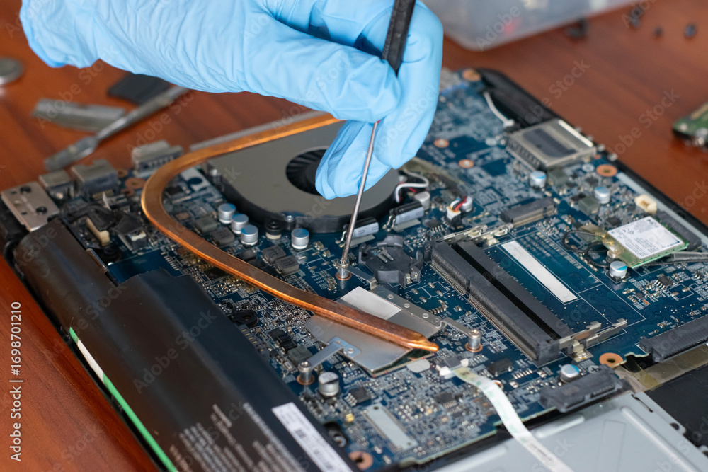 Naklejka premium A technician is repairing the motherboard of a laptop computer.