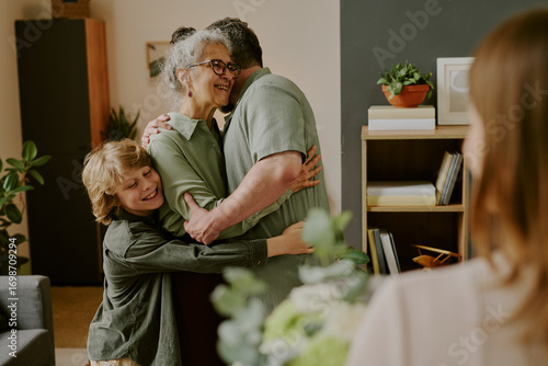 Fotografía Senior Caucasian woman smiling while hugging middle aged man and boy, standing t