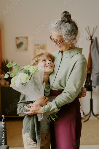 Photography Caucasian senior woman embracing Caucasian boy while holding bouquet of flowers,