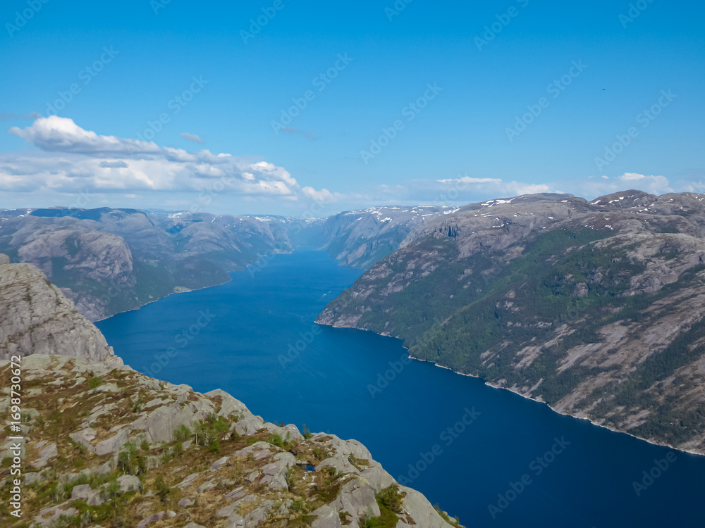 Fototapeta premium An awe-inspiring high-angle perspective from the Preikestolen trail captures the majestic Lysefjord, its blue water creating a contrast with the surrounding rugged mountains in Rogaland, Norway