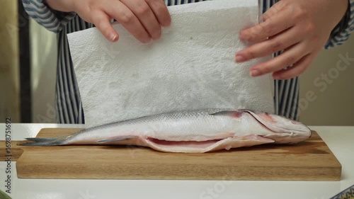 Female hands preparing the sea bass fish for cooking at home kitchen. Concepts of healthy eating and seafood