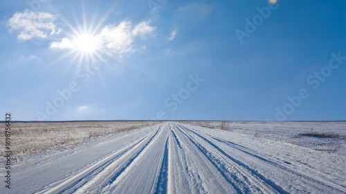  road among snowbound prairie in light of sparkle sun, winter travel time lapse scene