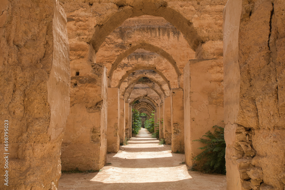 Obraz premium Old Ruined Arches in a Moroccan Kasbah - A view through an open wooden door of a series of old, crumbling arches in a kasbah or ancient fortress in Morocco.