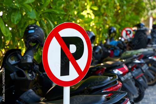 Warning sign - parking is prohibited. Full motorcycle parking near a no parking sign.