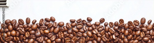 Pile of Roasted Coffee Beans on a White Surface With a Coffee Maker