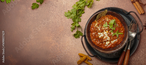 Dal makhani with cream and coriander leaves served in rustic bowl, accompanied by spices such as turmeric, cinnamon, and star anise, authentic Indian dish, copy space