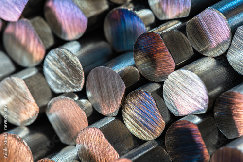 Close-up of cut non-ferrous metal rods stacked together, showing texture and reflections, industrial macro detail