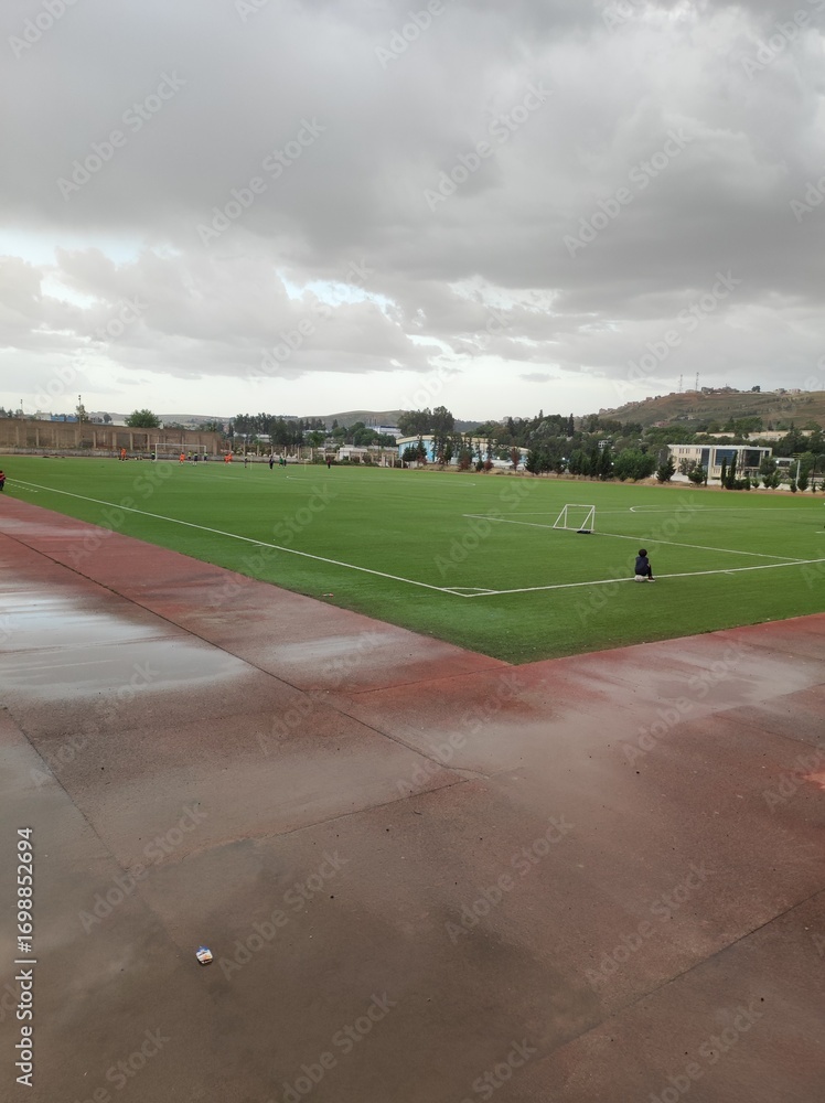 Fototapeta premium Empty football field after rain with cloudy sky