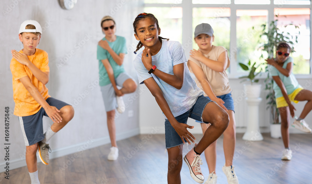 Naklejka premium Positive cheerful smiling children studying modern style dance in class indoors