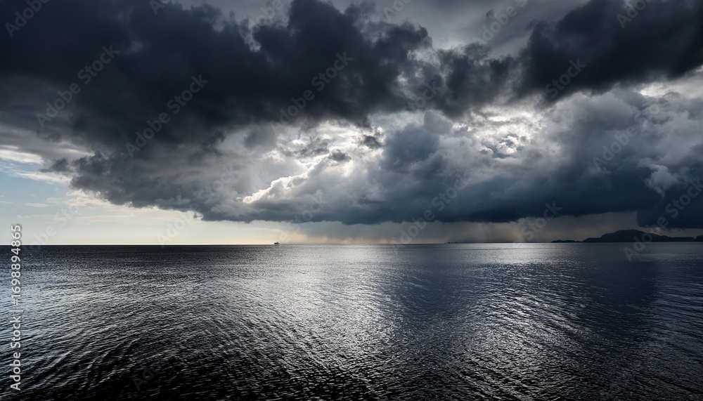 Obraz premium dark dramatic clouds over calm water reflecting distant light