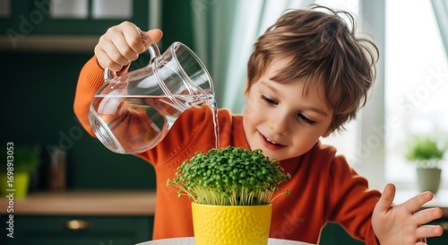 Boy is watering sprouts in a yellow pot with a glass pitcher indoors