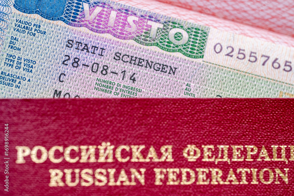 Obraz premium Schengen visa allows multiple entry to European Union, red Russian Federation passport in focus, travel ban restrictions and denied visas for Russian citizens, travel freedom across Europe