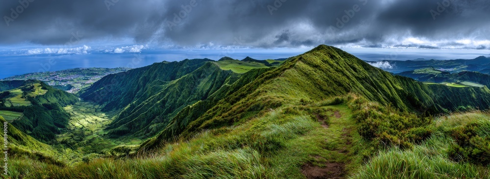Fototapeta premium Lush green mountain range panorama under dramatic sky