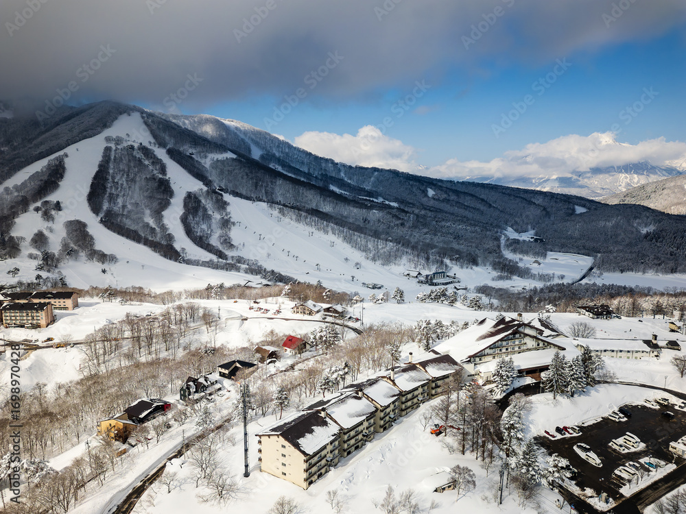 Naklejka premium Aerial drone view of Madarao ski resort with snowy slopes and village in Nagano, Japan