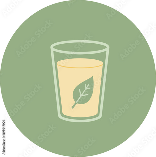 Transparent glass with light orange liquid and floating green leaf on circular green background