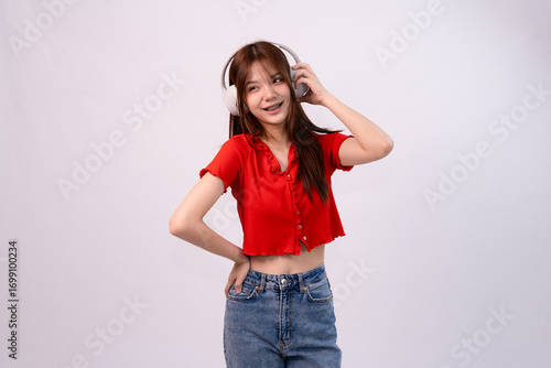 young beautiful woman enjoying music with headphones in stylish casual outfit on studio background