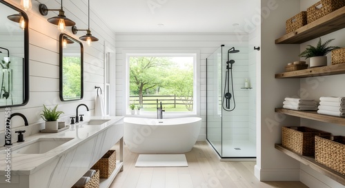 Bright and airy bathroom featuring a white freestanding tub, marble countertops, wooden shelves, and a large window overlooking a verdant landscape. Modern farmhouse style. 