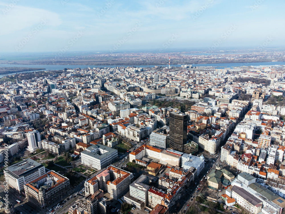 Fototapeta premium Aerial view over dense urban center with red roofs, high-rise buildings, and river in the background. g.
