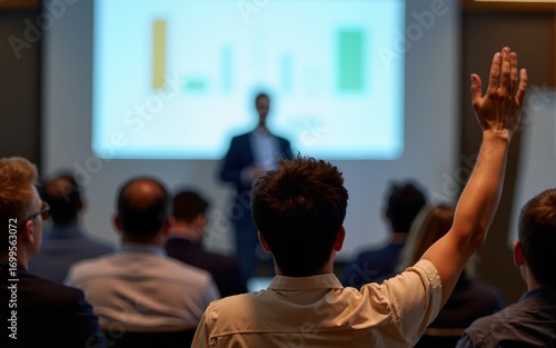 Rear view of seminar attendee raising hand and asking questions about financial report. High quality
