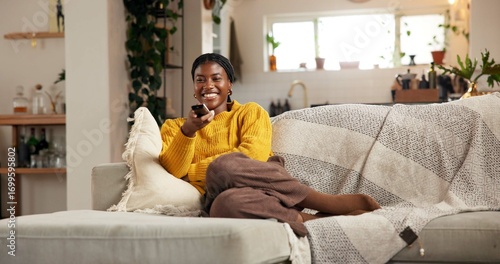 Foto Happy, black woman and watching tv on sofa with remote for channel, movie or entertainment in home