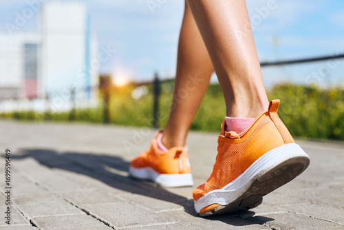 Female feet in sneakers walking on the sidewalk