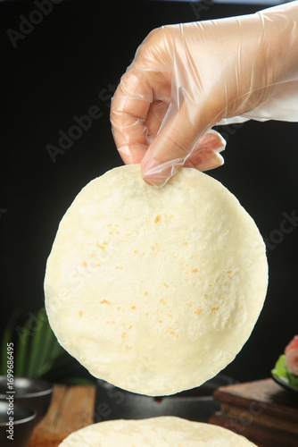 Chef Hand in Glove Holding Fresh Flour Tortilla in Professional Kitchen Food Preparation