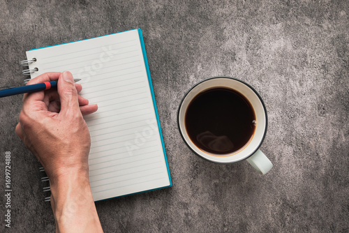 Hand writing on Notebook with Cup of Coffee on Table