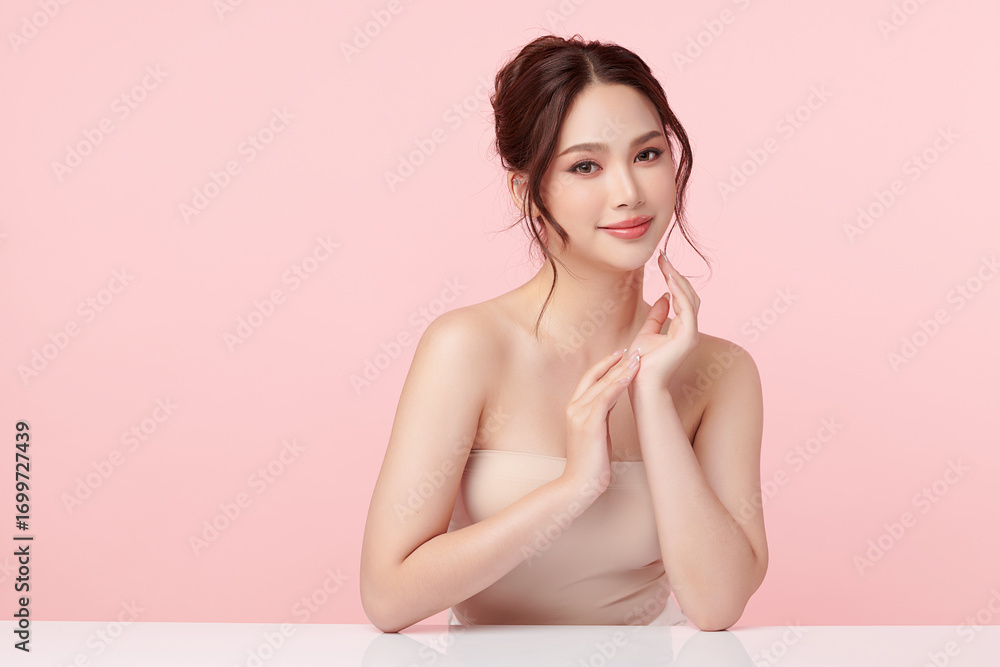 Obraz premium A beautiful young Asian woman with clean, fresh skin against a pink background. Skincare, facial treatment, cosmetology, beauty, and spa. An elegant portrait of an Asian woman.
