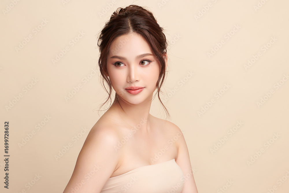 Obraz premium A beautiful young Asian woman with clean, fresh skin against a beige background. Skincare, facial treatment, cosmetology, beauty, and spa. An elegant portrait of an Asian woman.