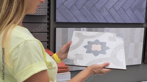 Woman choosing decorative ceramic tile with floral pattern in hardware store