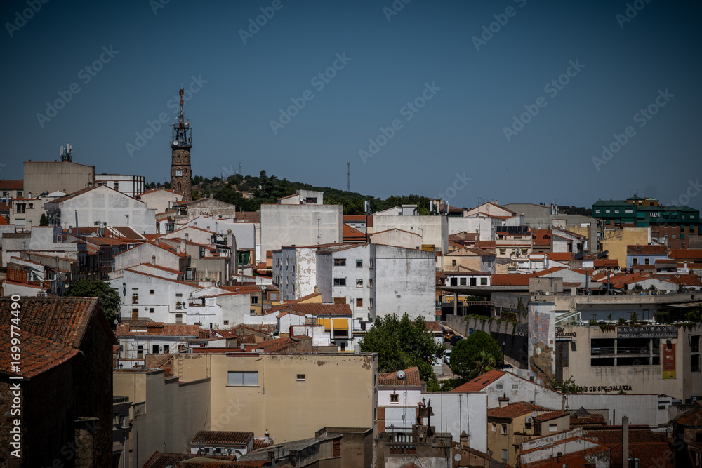 Fototapeta premium Vista panorámica del casco histórico de la ciudad española de Cáceres con vistas a los tejados de tejas marrones de edificios antiguos alrededor de la plaza principal en el soleado día de verano