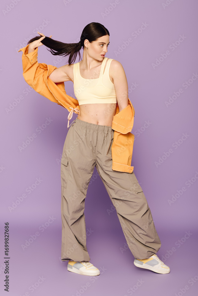 Fototapeta premium A stylish young woman poses confidently, showcasing her trendy outfit and flair.