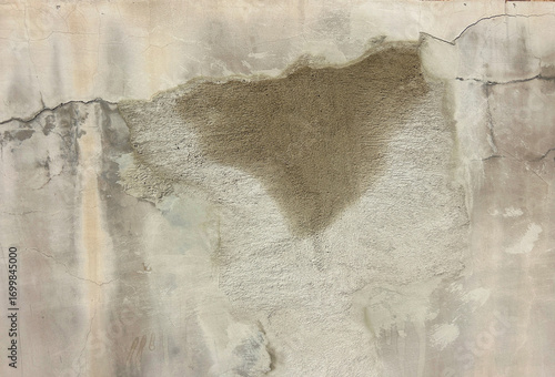 Close-up texture of a damaged wall with peeling paint and patches of moisture stains