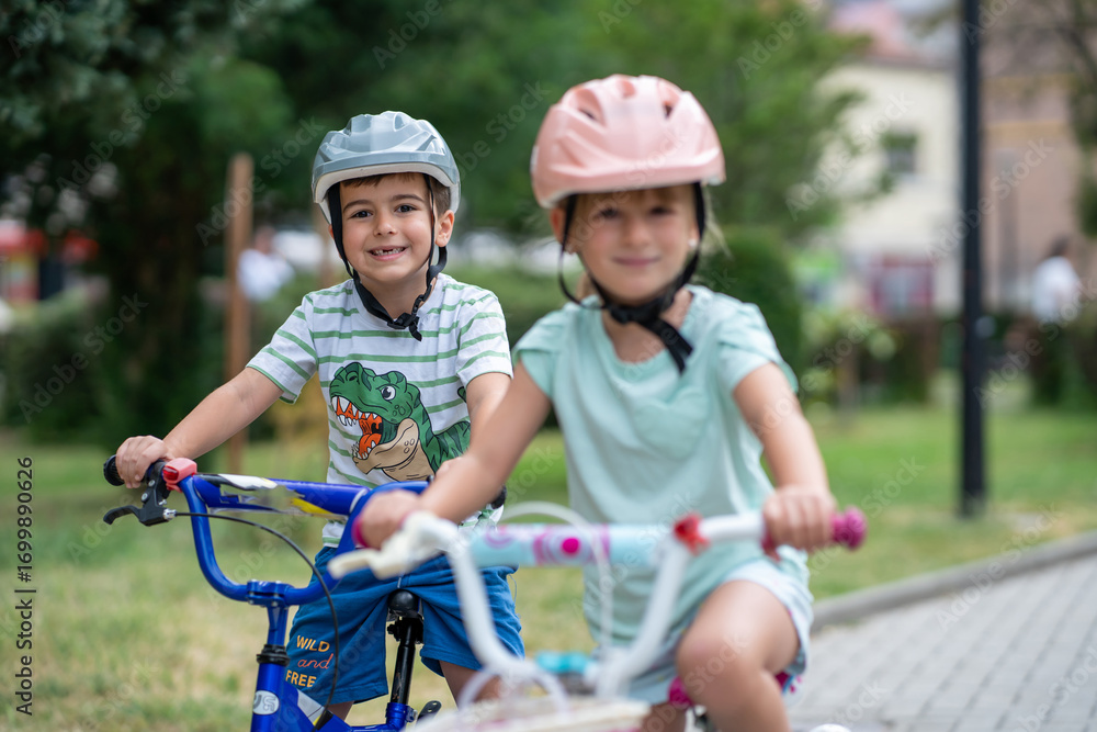 Obraz premium Two confident youngsters enjoy a bike ride in the city, showcasing their friendship and joy. The image highlights health and the importance of safety measures like wearing helmets. 