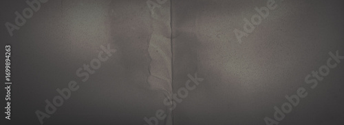 Dark wide panoramic background. Old fade paper texture. Dark panorama with empty space. Rough faded surface. Spots and grain. Blank vintage background for design. Shaded retro texture with vignette.