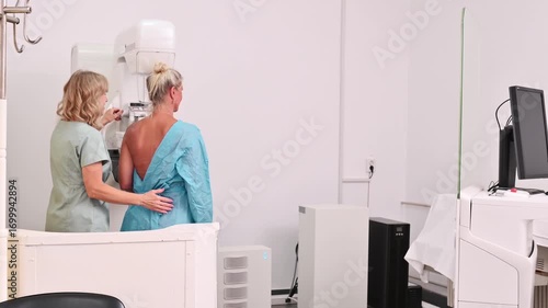 50-year-old woman undergoes mammography procedure on special medical equipment mammograph with the help of assistant in modern clinic. Regular medical examination, screening for breast cancer	