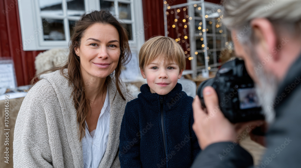 Obraz premium A cheerful woman and a young boy pose together for a photo in a festive outdoor setting filled with holiday decorations and warm ambiance, capturing shared moments of joy.