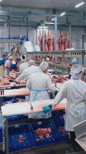 Factory for the production of meat products, a workshop for cutting carcasses. Meat processing shop at a sausage factory. Unidentified meat processing plant workers at work, food industry.