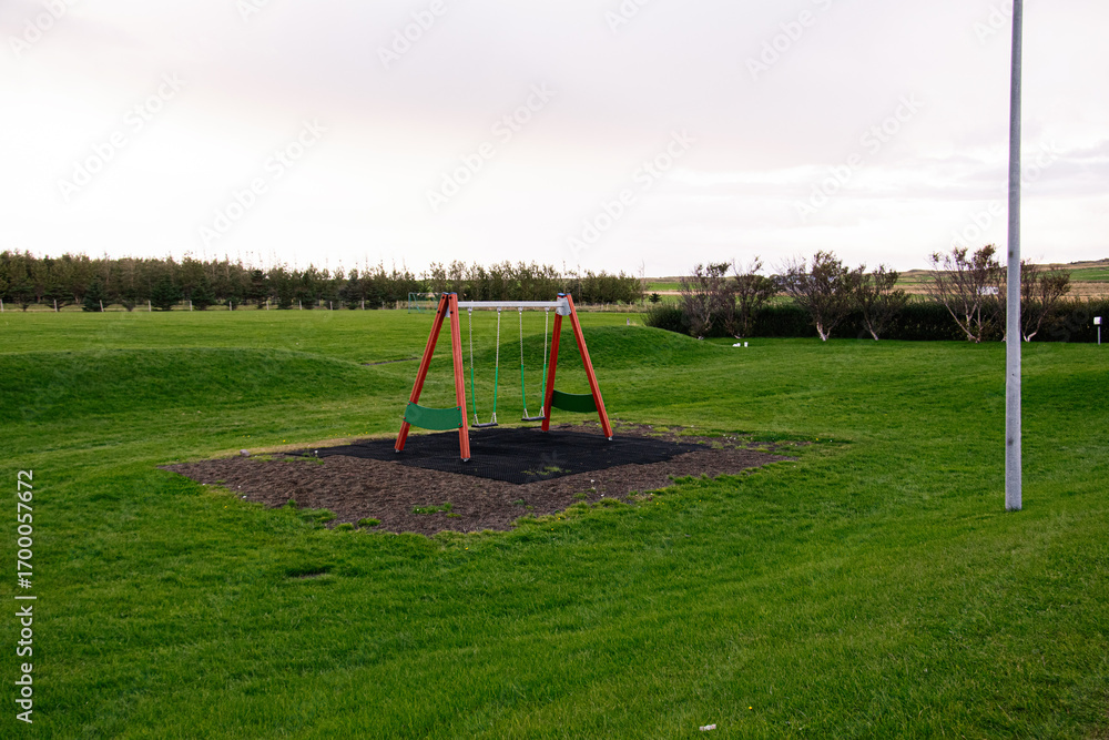 Fototapeta premium Playground swing set in Akranes surrounded by vibrant green grassy fields