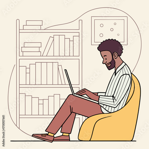 Bearded black man sitting in ergonomic chair, typing on laptop with bookshelf in background.