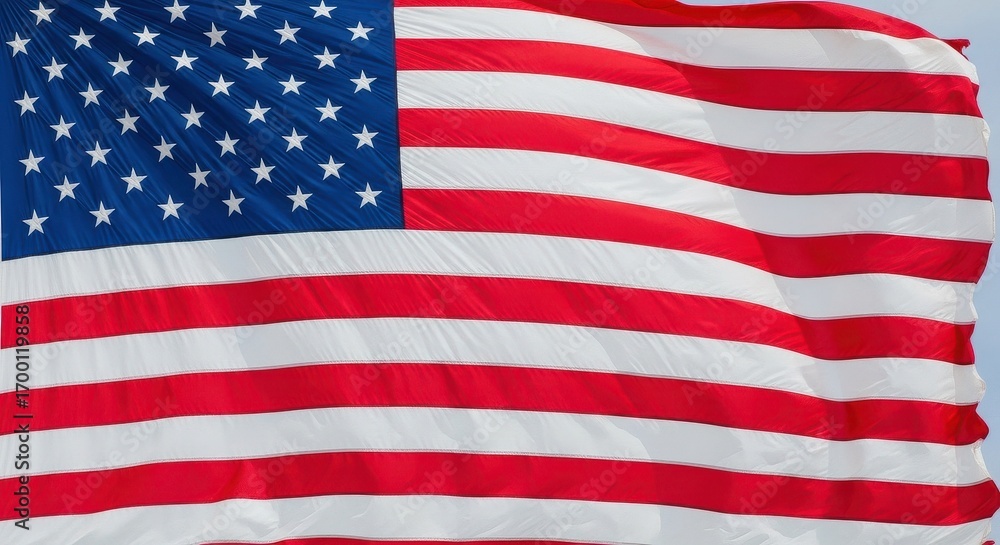 Fototapeta premium Waving American Flag Against the Blue Sky Symbol of Freedom and Patriotism