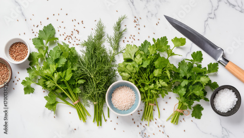 Fresh parsley and dill bunches with salt, coriander seeds, and knife on marble kitchen surface, ready for cooking