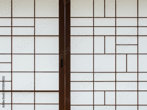 A close-up of a traditional Japanese shoji screen featuring a brown wooden grid pattern with translucent white paper panels and a central sliding frame.