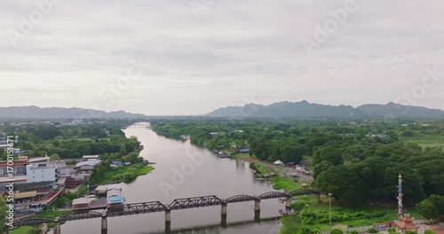 Scenic View of River Kwai with Iconic Bridge in Kanchanaburi Surrounded by Lush Greenery and Distant Mountains Historic River Kwai Flows Under Bridge