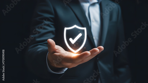 Business Protection: A person holds an illuminated shield with a checkmark, symbolizing security, safety, and approval within the business world, a perfect image for representing protection.