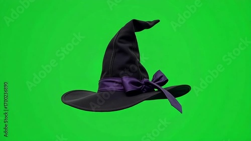 Spooky witch hat with purple ribbon and bow on a green background