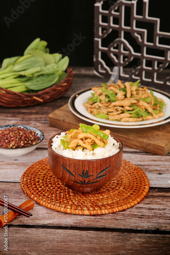 Stir-fried pork with peppers and chili over rice in wooden bowl - Asian cuisine on rustic wooden table