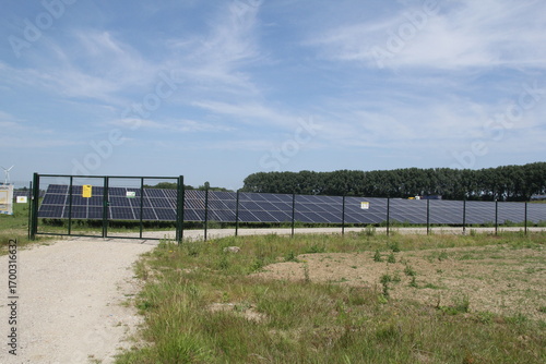 a large solar park with solar panels in the countryside and a blue sky