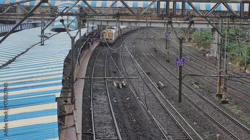 A Mumbai local train arriving at a platform, with multiple railway tracks on one side